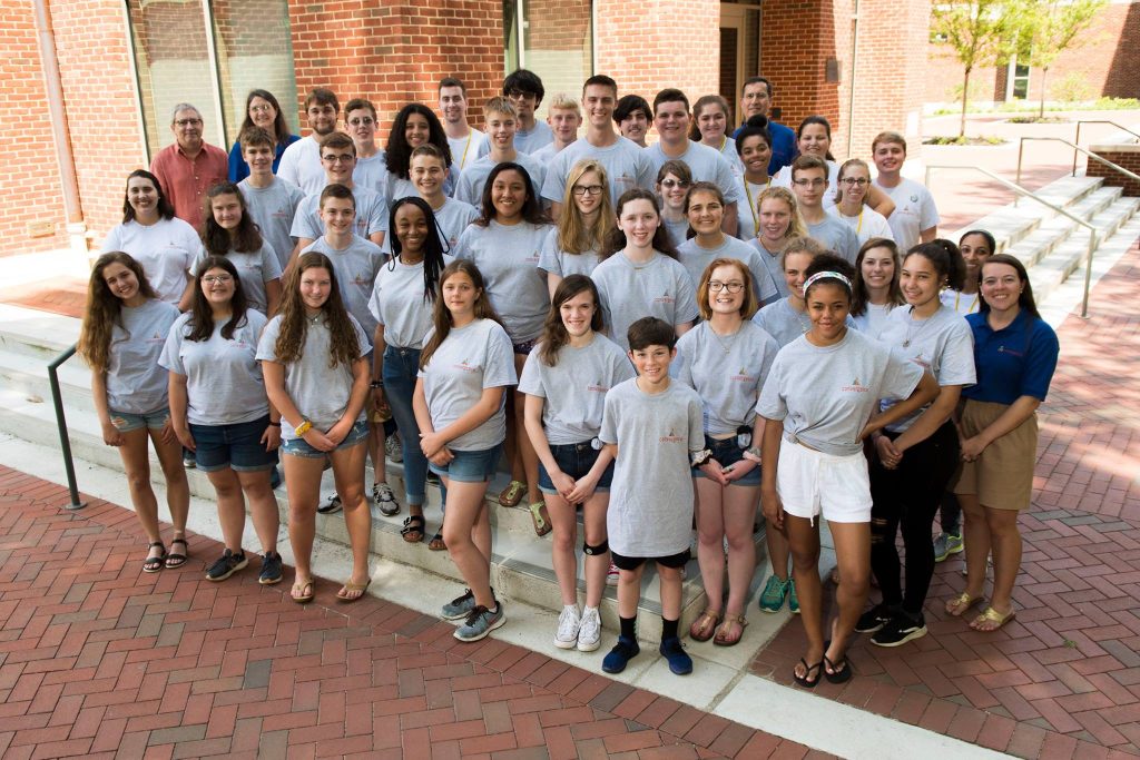 A group of convergence students gathered on the stairs outside in front of a building